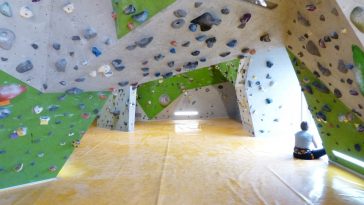 Sala de un rocódromo lleno de presas y colchonetas
