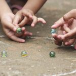 Juegos de las canicas. Dos niños jugando con canicas