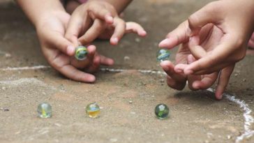 Juegos de las canicas. Dos niños jugando con canicas