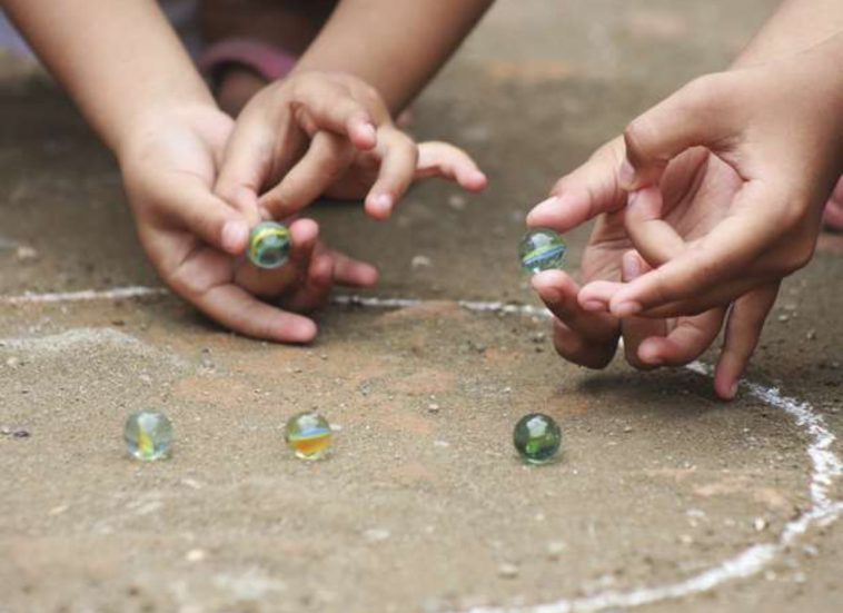 Juegos de las canicas. Dos niños jugando con canicas