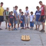 Entre los juegos tradicionales está el juego hoyetes, en la foto se puede ver el grupo de personas al rededor de la tabla