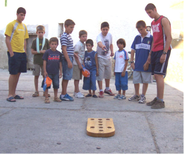 Entre los juegos tradicionales está el juego hoyetes, en la foto se puede ver el grupo de personas al rededor de la tabla
